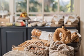 A kitchen counter with various breads and baked goods, including a braided loaf and a basket of eggs.