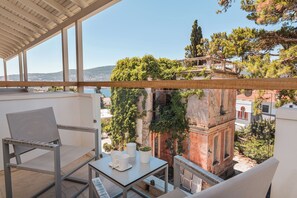 A balcony with a table, chairs, and a view of a historic building and trees.