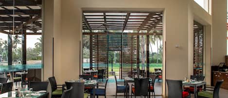 Un vaste espace extérieur aménagé pour les repas, avec de nombreuses tables et chaises, de grandes fenêtres et une vue sur le paysage environnant.