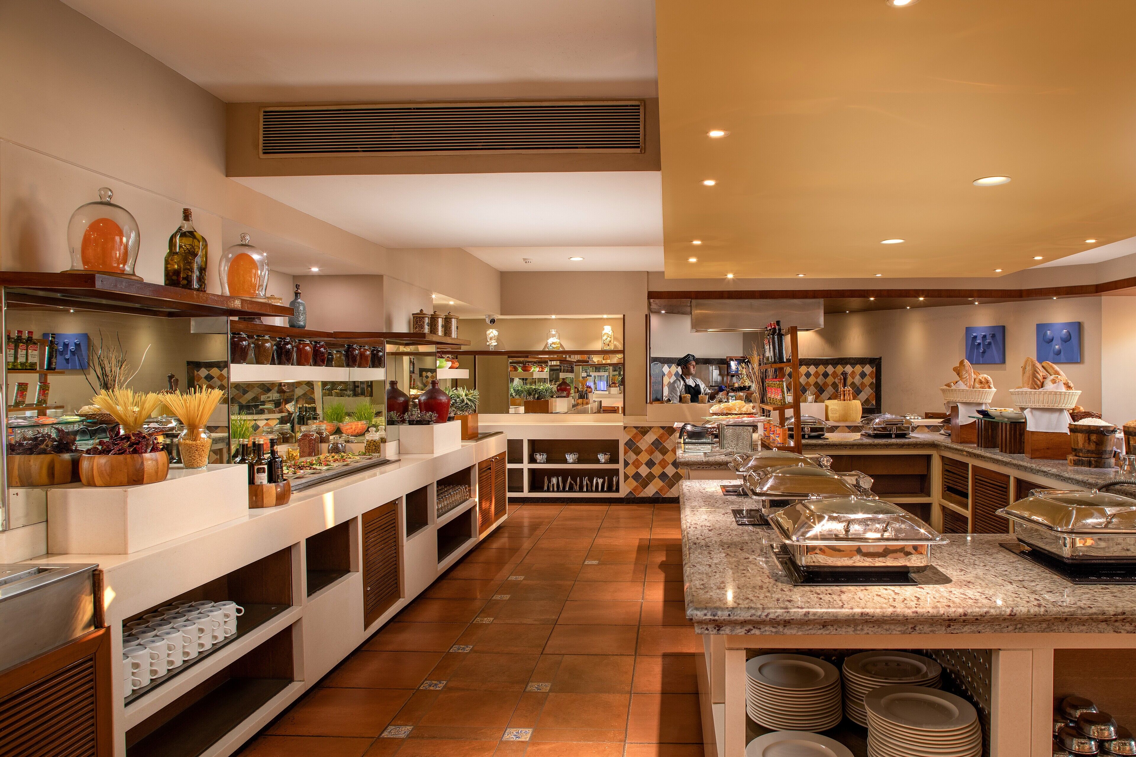 A spacious hotel lobby with a buffet area, a reception desk, and a seating area.