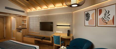 Una habitación de hotel con una cama, un escritorio, una silla, un televisor y obras de arte en la pared.