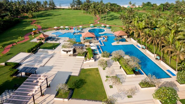 Un resort con varias piscinas, palmeras y vistas al océano.
