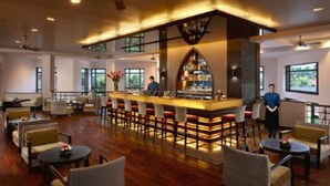 Un amplio bar con una barra alta, diversas opciones de asientos y vistas al exterior a través de grandes ventanales.
