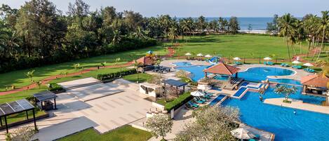 Un resort con varias piscinas, tumbonas y un césped bien cuidado.