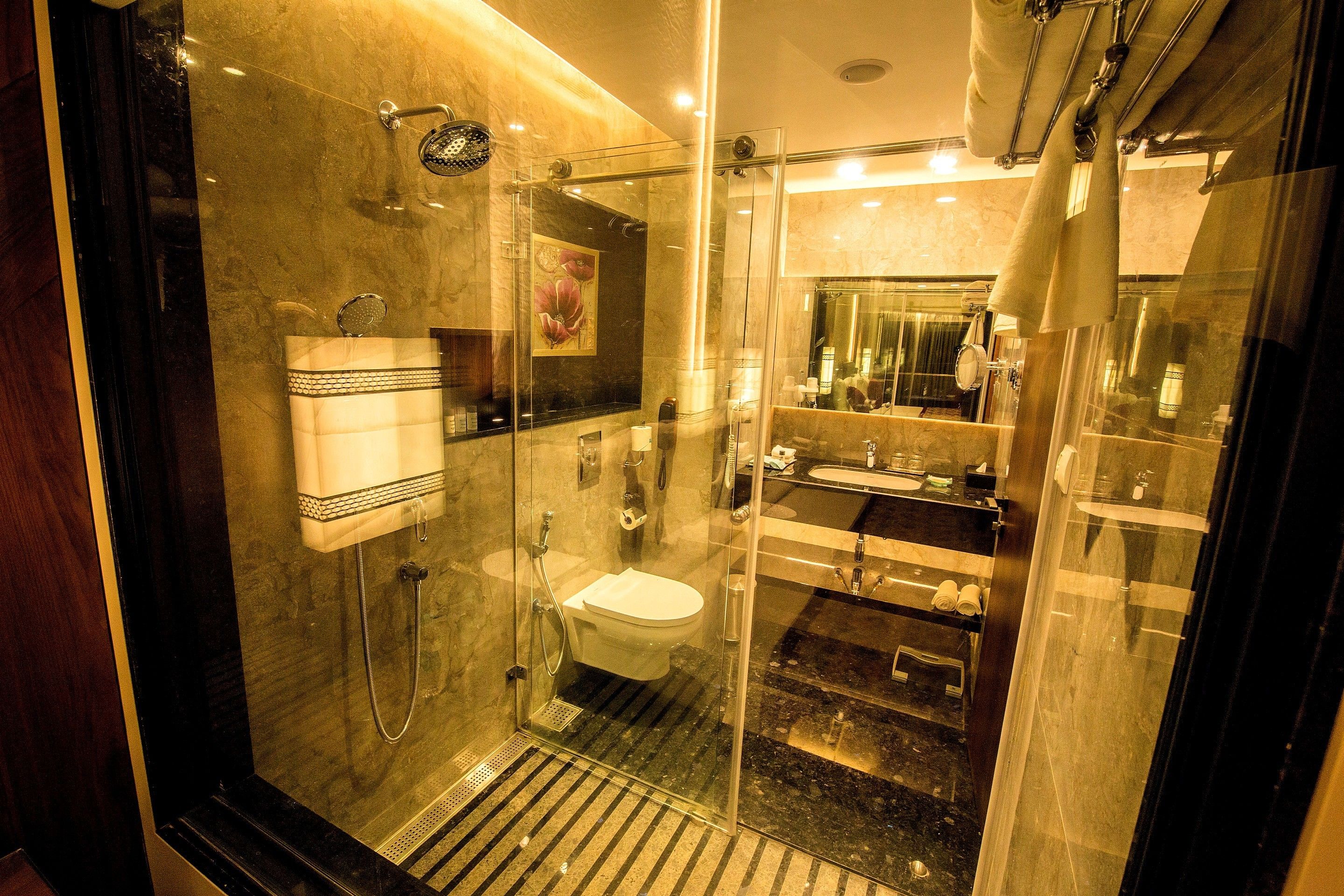 A modern bathroom with a glass-enclosed shower, a toilet, and a sink.