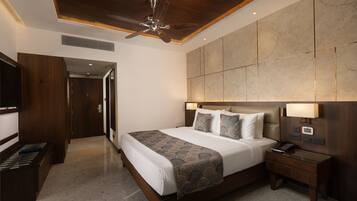 A hotel room with a large bed, bedside lamps, a nightstand, a TV, and a ceiling fan.