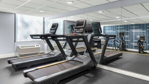 Un gimnasio con cintas de correr, bicicletas estáticas y un espejo grande.