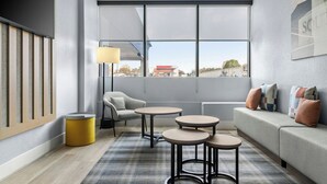 Una habitación de hotel moderna con un ventanal grande, un sofá, una silla y una mesita.