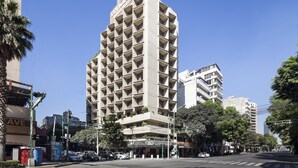 Un hotel de varios pisos con un diseño arquitectónico moderno, que destaca por su entrada principal y balcones.