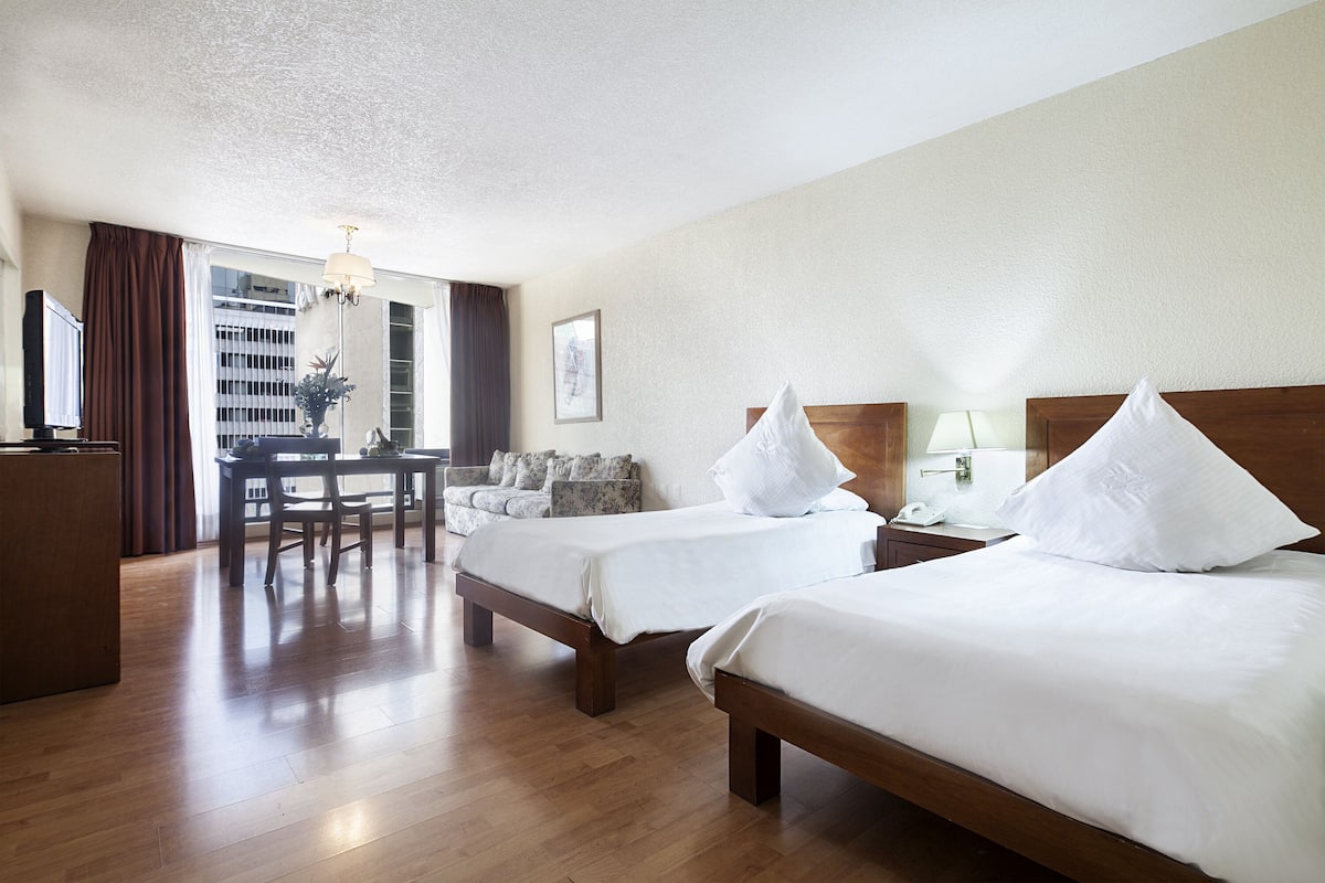 Une chambre d’hôtel avec deux lits, un bureau et une chaise.