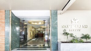 La entrada de un hotel con un mostrador de recepción de mármol, una zona de recepción y un cartel que indica el nombre del hotel y el número de la suite.
