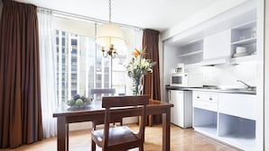 Una cocina moderna con armarios blancos, una mesa de comedor con un florero y vistas a la ciudad a través de amplios ventanales.