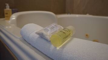 A bathtub with a white towel and two bottles of bath products.