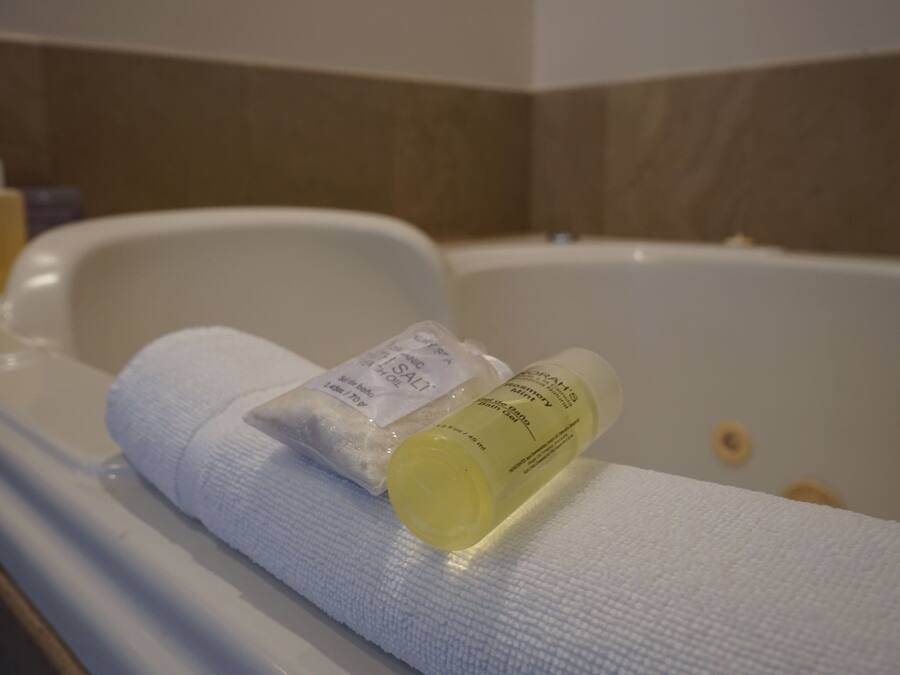 A bathtub with a white towel and two bottles of bath products.