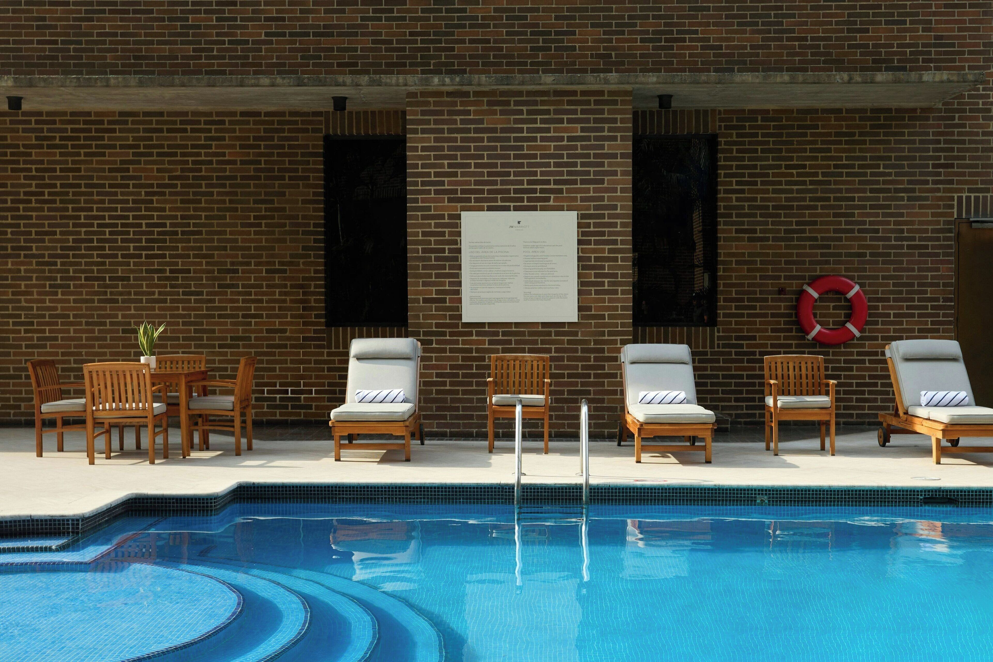 A swimming pool with lounge chairs and a brick wall.