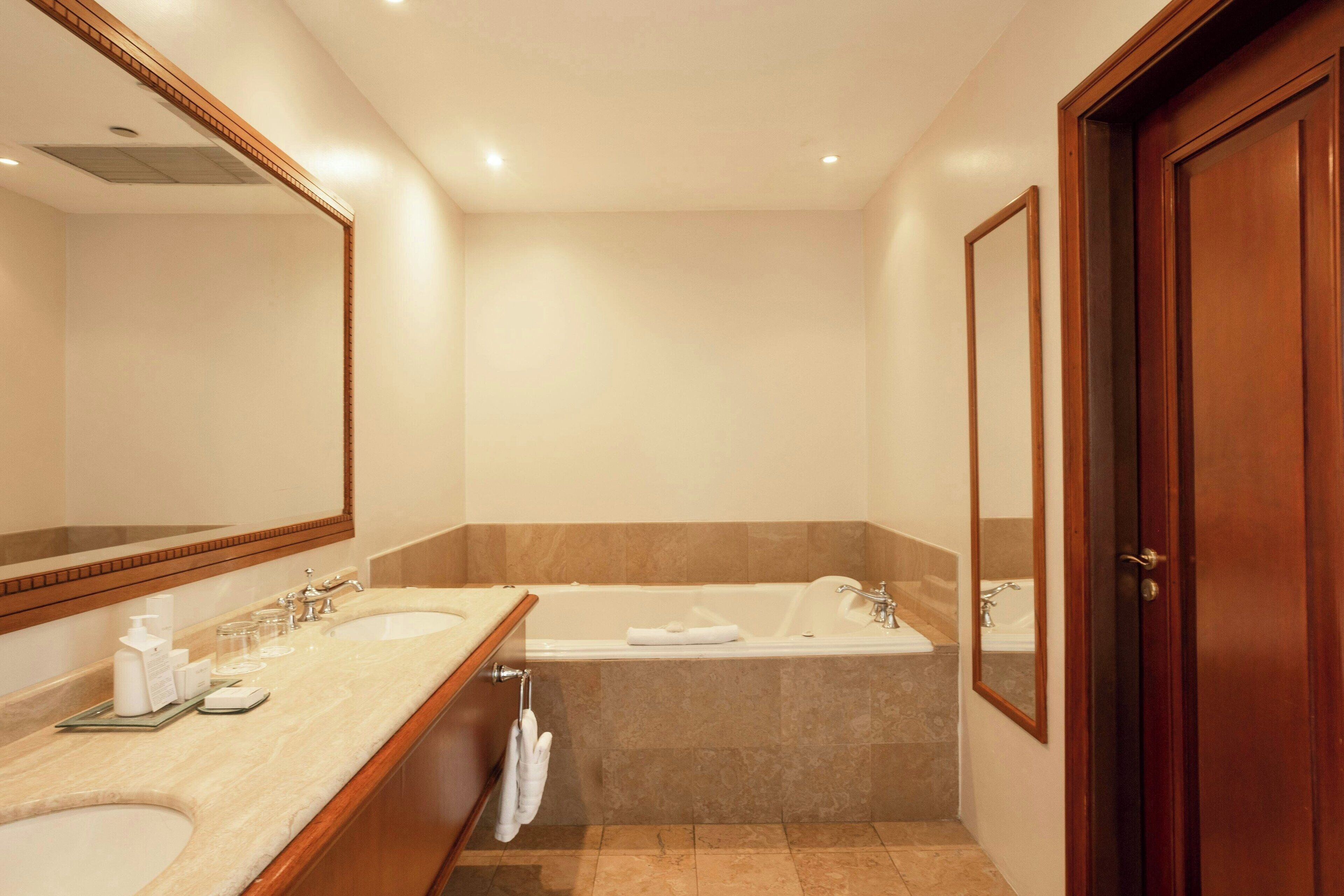 A bathroom with two sinks, a bathtub, and a large mirror.