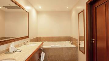 A bathroom with two sinks, a bathtub, and a large mirror.