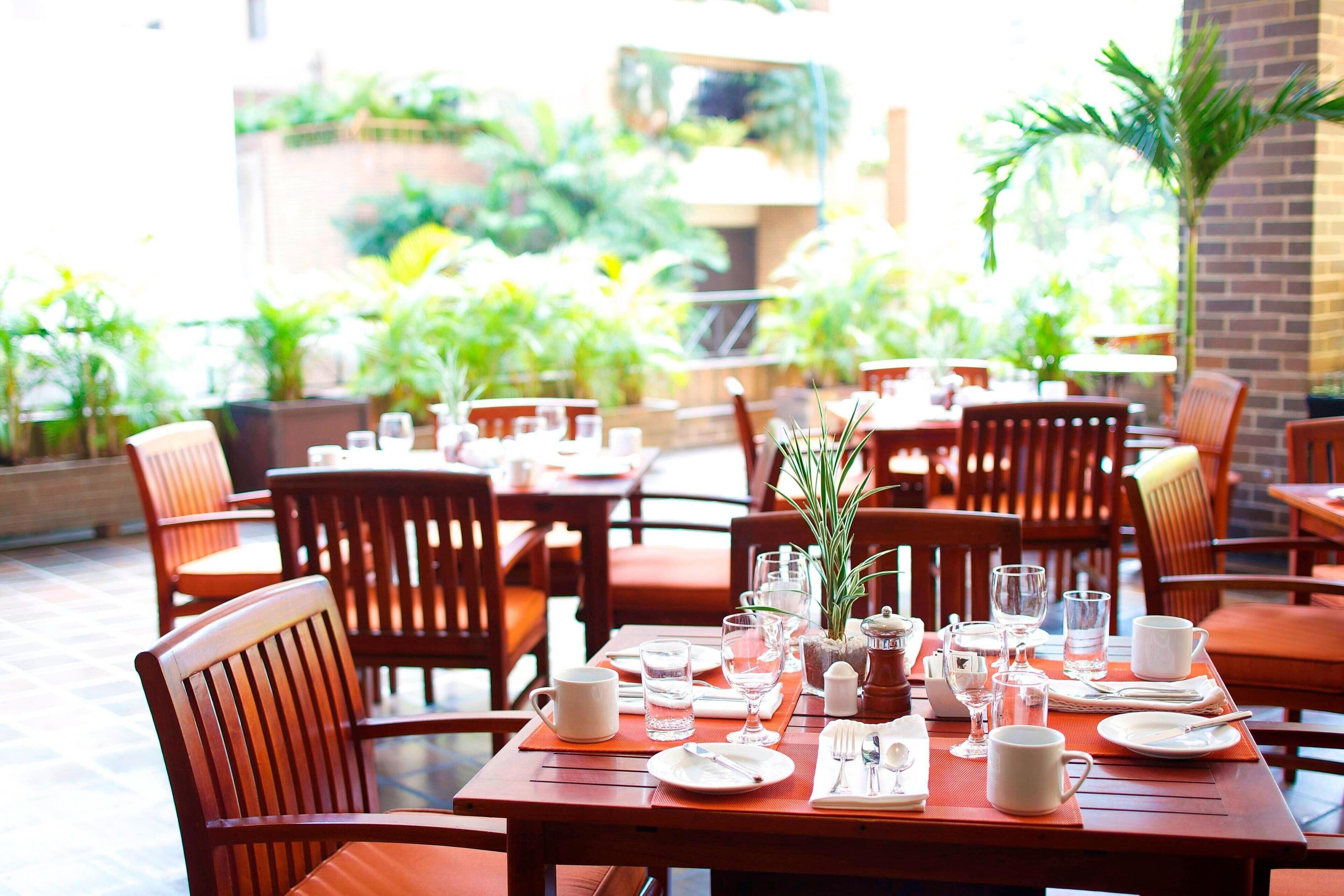 A restaurant with wooden tables and chairs, set with plates, glasses, and cutlery.