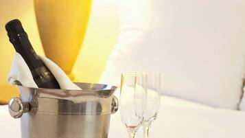 A metal bucket with a bottle of champagne, two empty glasses, and a plate of food on a tray.