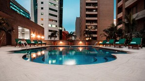 Una piscina con sillones de descanso y un muro de ladrillo.