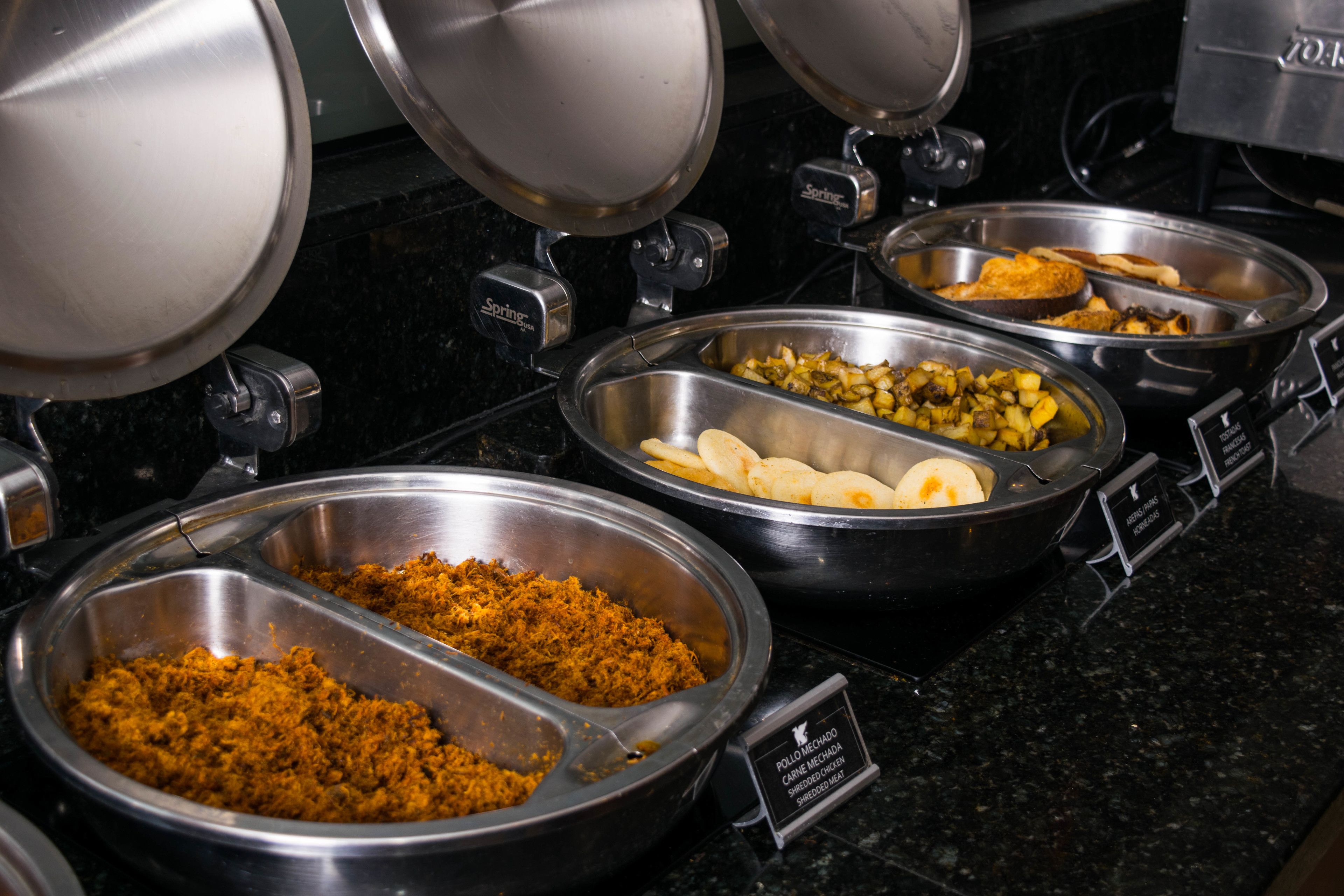 A buffet with various food options including shredded chicken, potatoes, and other dishes.