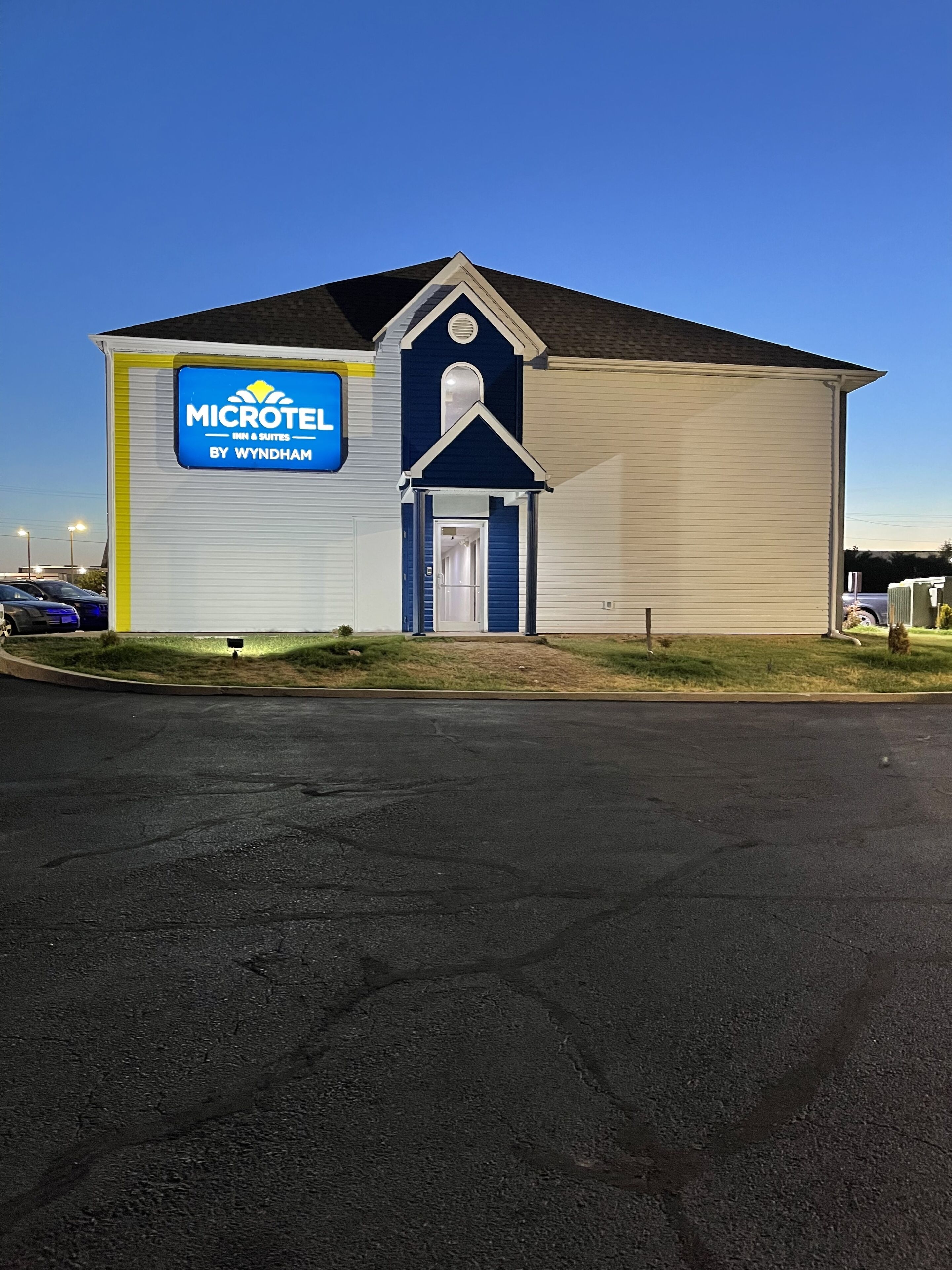 A Microtel Inn & Suites building with a blue and white exterior, a central entrance, and a parking lot in the foreground.