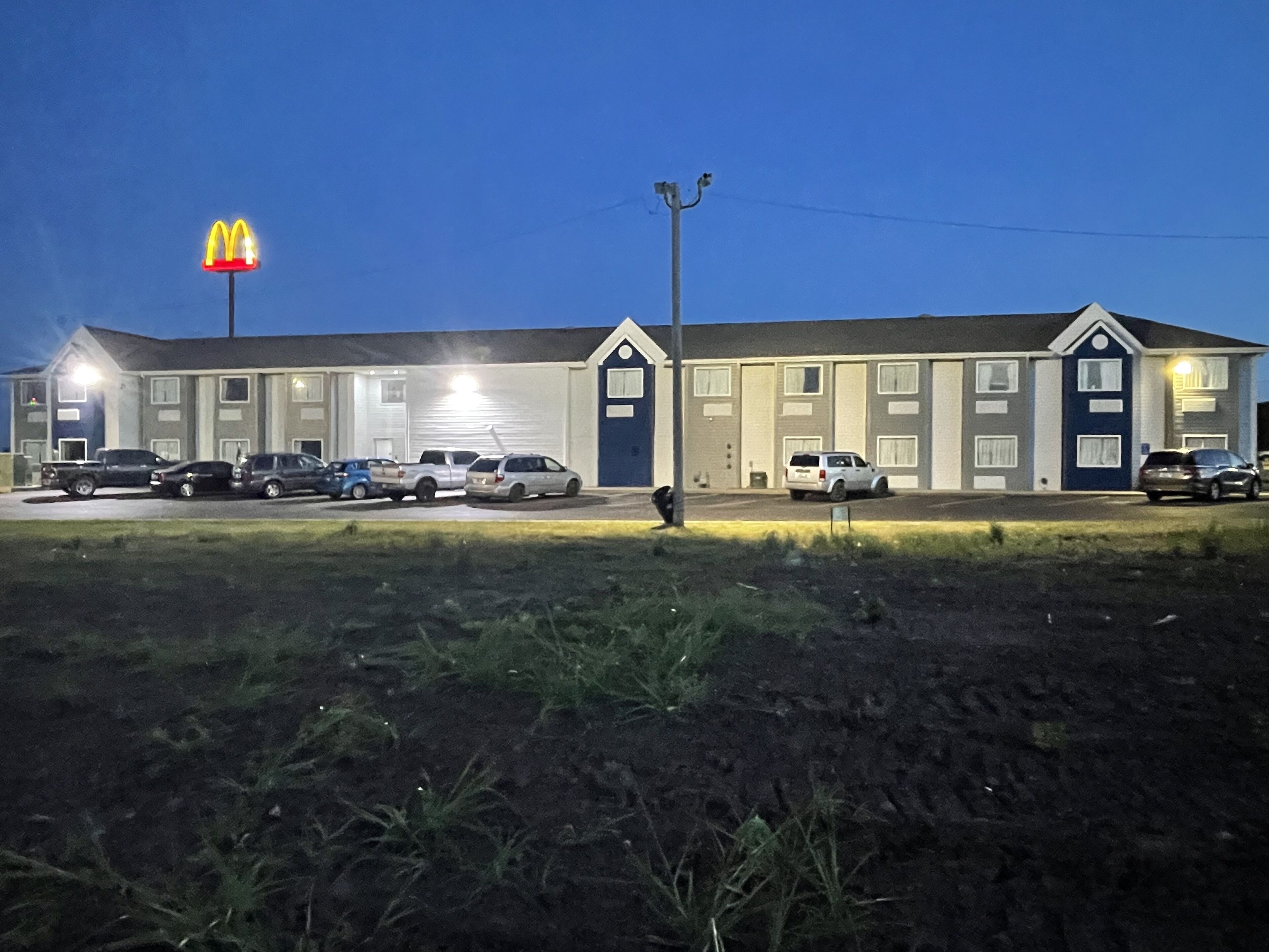 Un motel avec une enseigne McDonald's, de nombreuses places de stationnement et une façade bien éclairée.