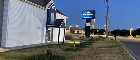A Microtel Inn & Suites by Wyndham with a white exterior and a blue roof, located near a road with a McDonald's sign in the background.