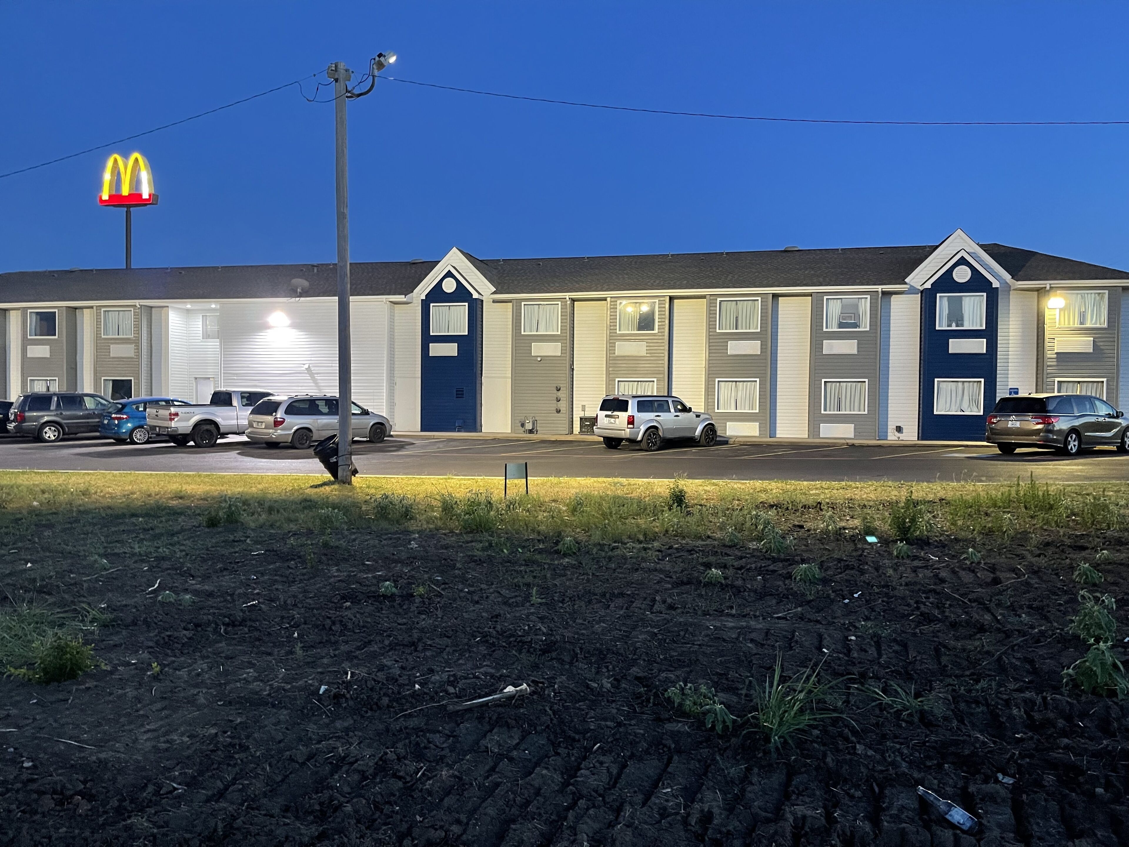 A motel with a McDonald's sign, multiple parking spaces, and a well-maintained lawn.