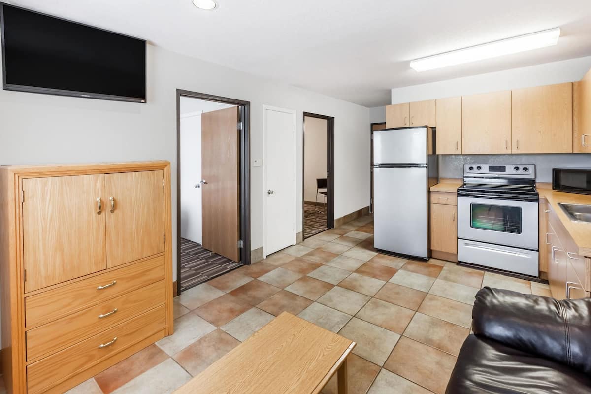A compact kitchen with a refrigerator, stove, microwave, and wooden cabinets.