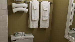 A bathroom with a toilet, a sink, and towels hanging on a rack. - Inn@Bayshore (San Mateo)