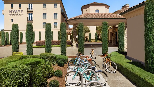 A Hyatt Regency hotel with a well-maintained garden, bicycles, and a clear blue sky. - Hyatt Regency Sonoma Wine Country (Santa Rosa)