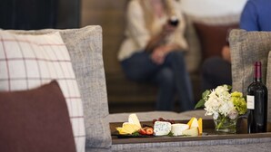 A seating area with a tray of cheese and grapes, a bottle of wine, and a vase of flowers. - Hyatt Regency Sonoma Wine Country (Santa Rosa)