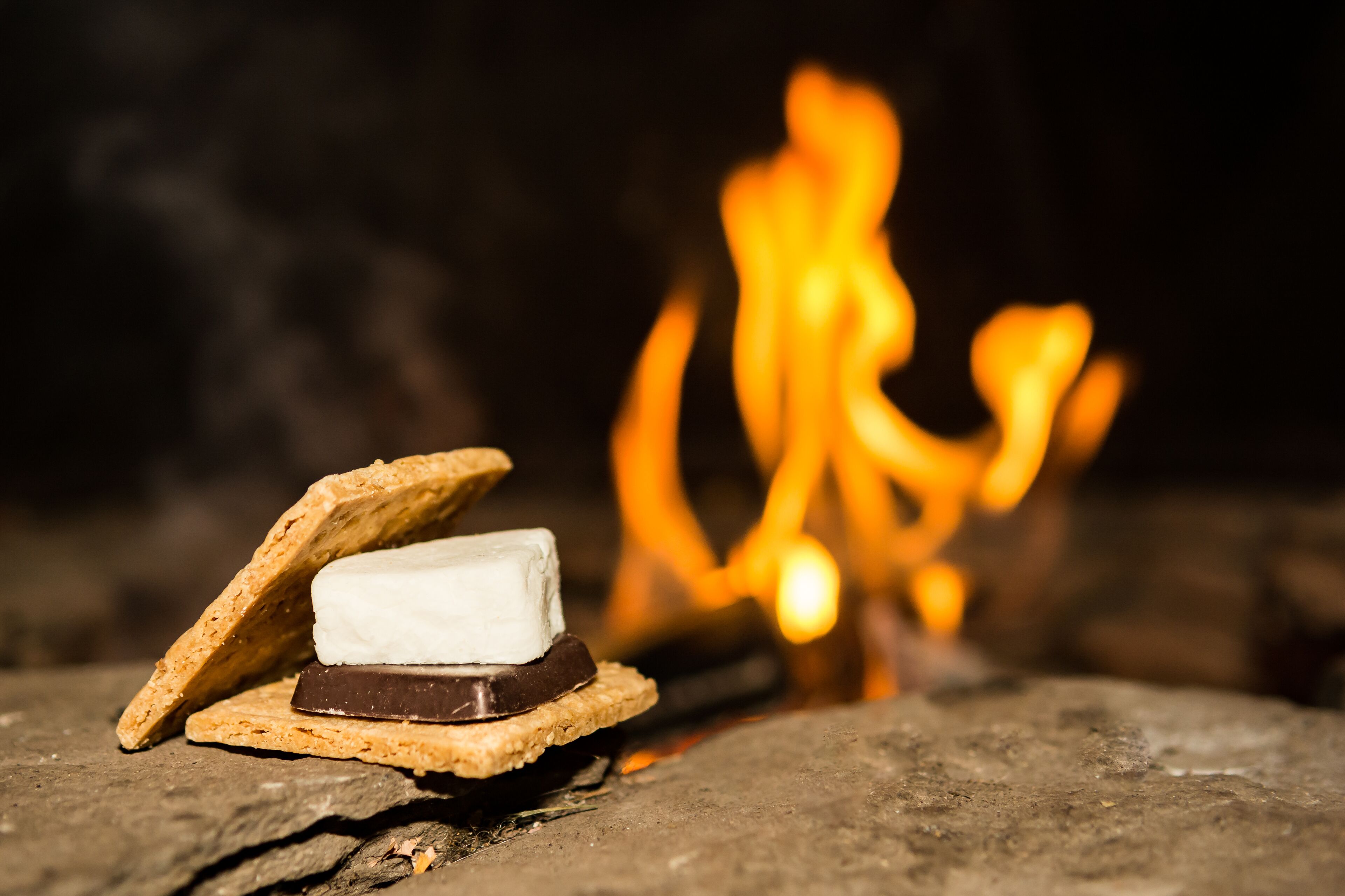 A campfire with a marshmallow and chocolate bar on a graham cracker.