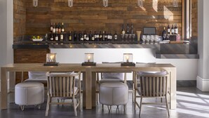 A modern bar area with a wooden wall, a long countertop displaying wine bottles, and pendant lighting. - Hyatt Regency Sonoma Wine Country (Santa Rosa)
