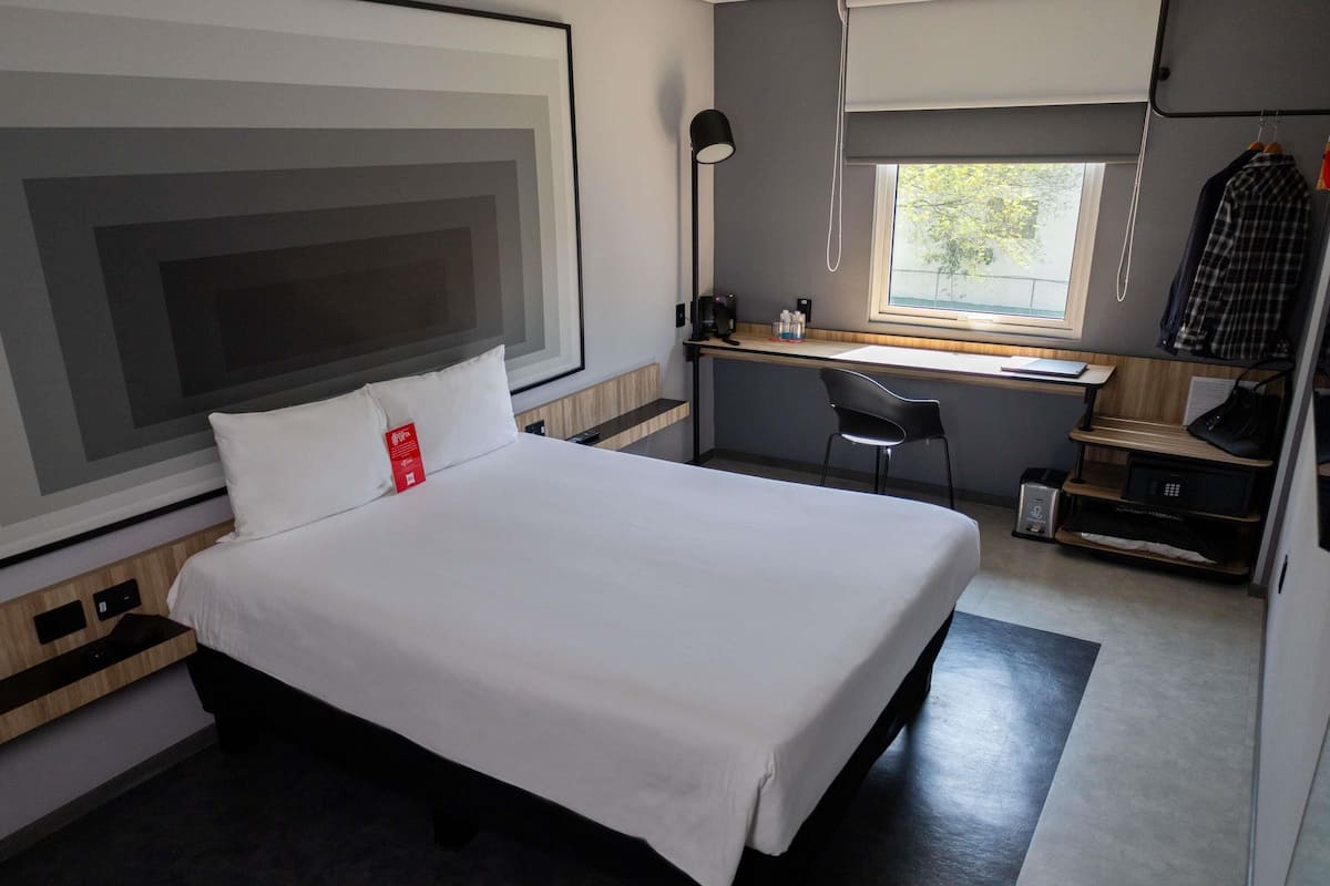 Habitación de hotel con cama, escritorio, silla y ventana con vistas.