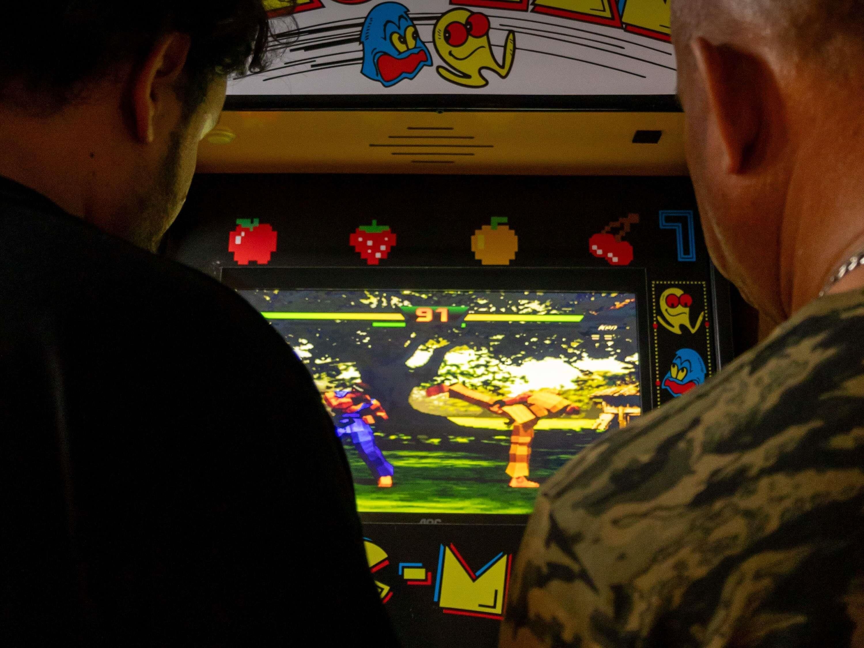 Una consola de videojuegos con una pantalla mostrando un juego, rodeada de gente.