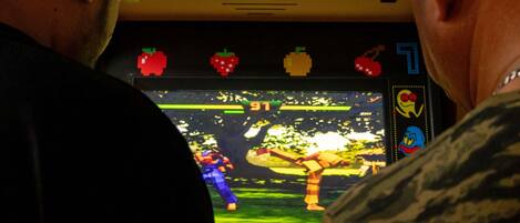 A video game console with a screen displaying a game, surrounded by people.