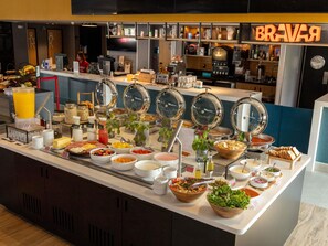 Mostrador de buffet con diferentes alimentos y una estación de café.