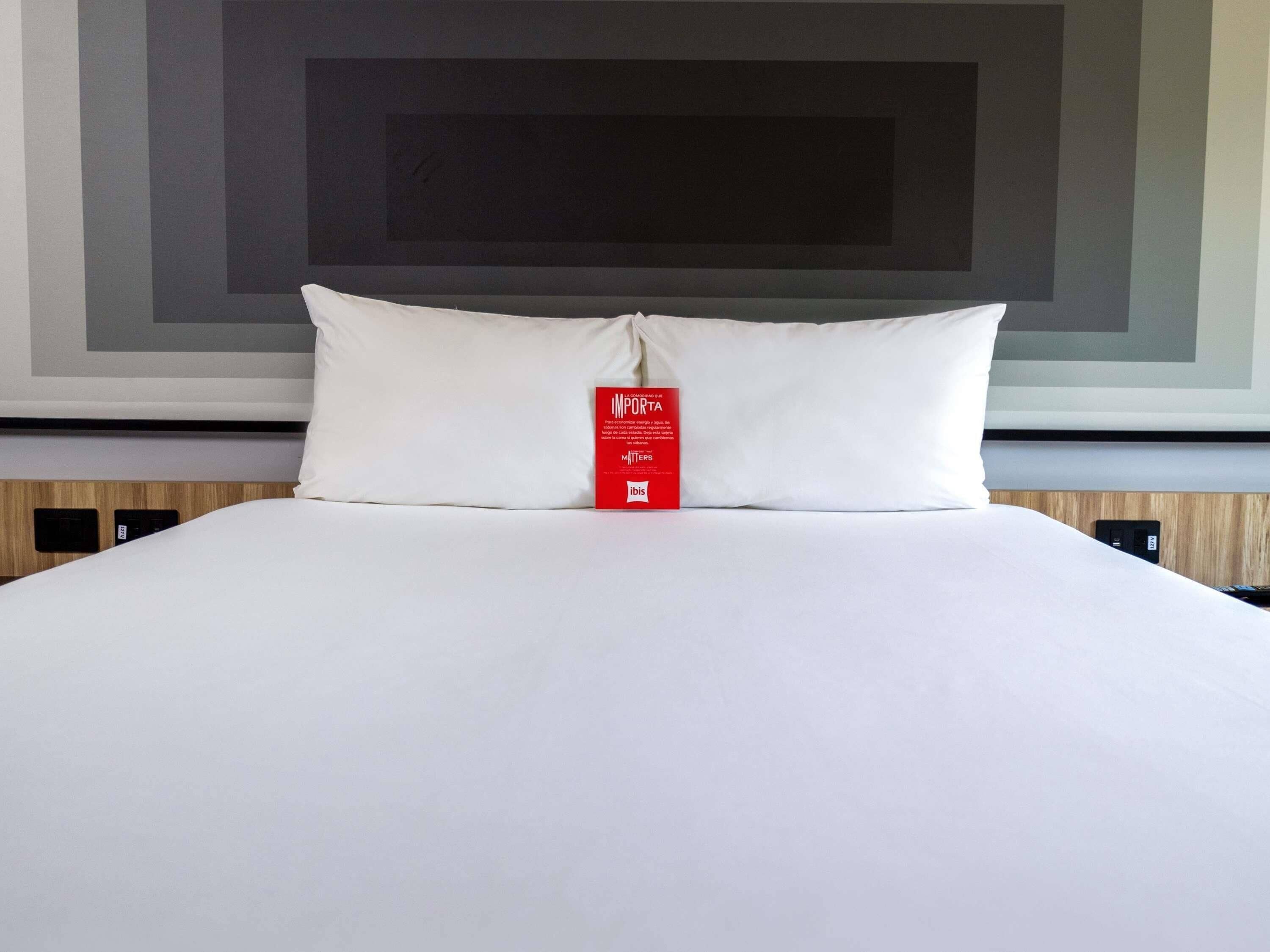 Un lit bien fait, avec un oreiller blanc et une étiquette rouge.