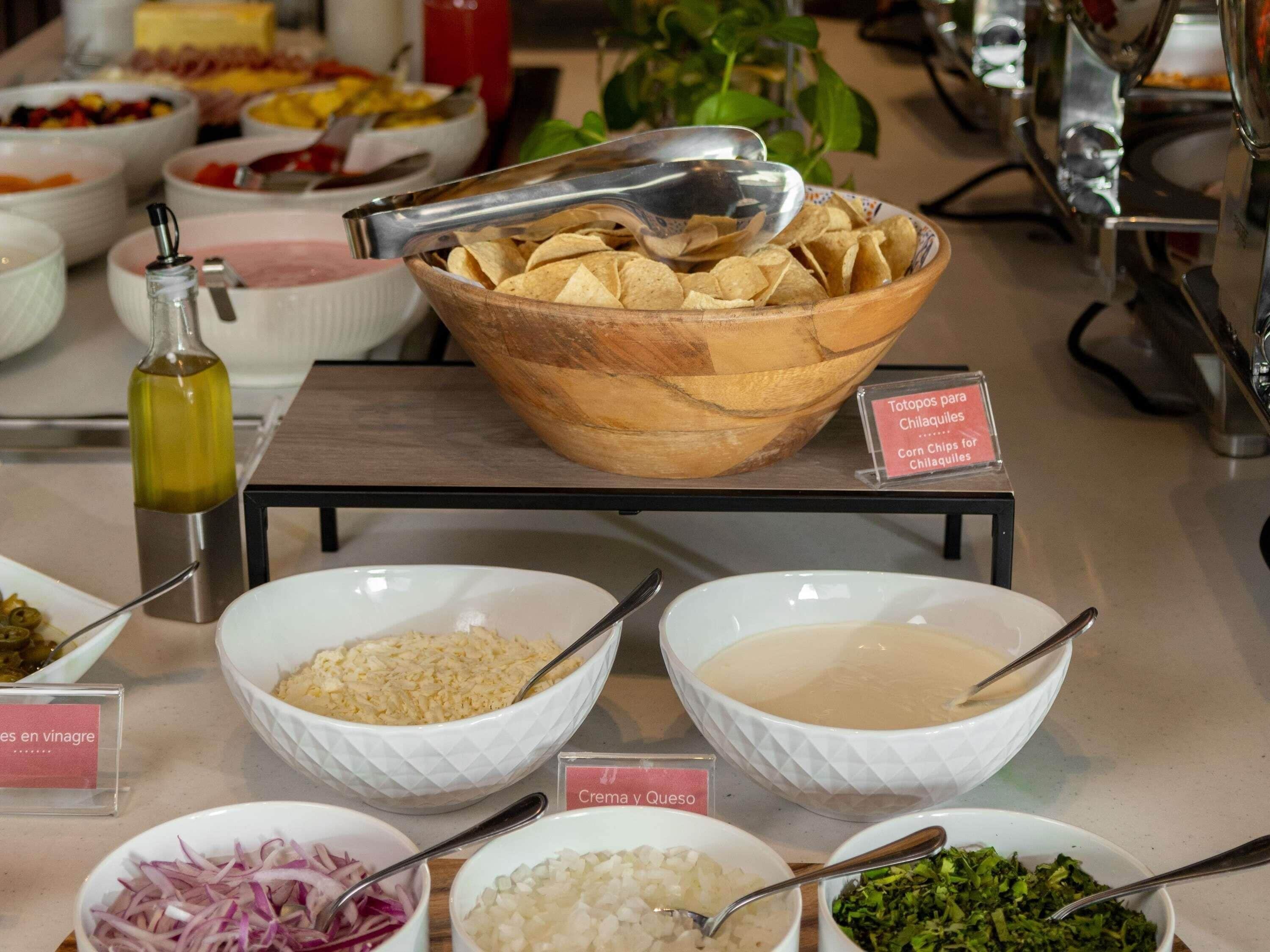 A buffet with various food items including rice, beans, and a bowl of chips.