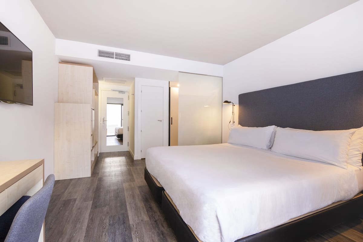 Ein modernes Hotelzimmer mit einem großen Bett, einem Schreibtisch und einem Kleiderschrank.