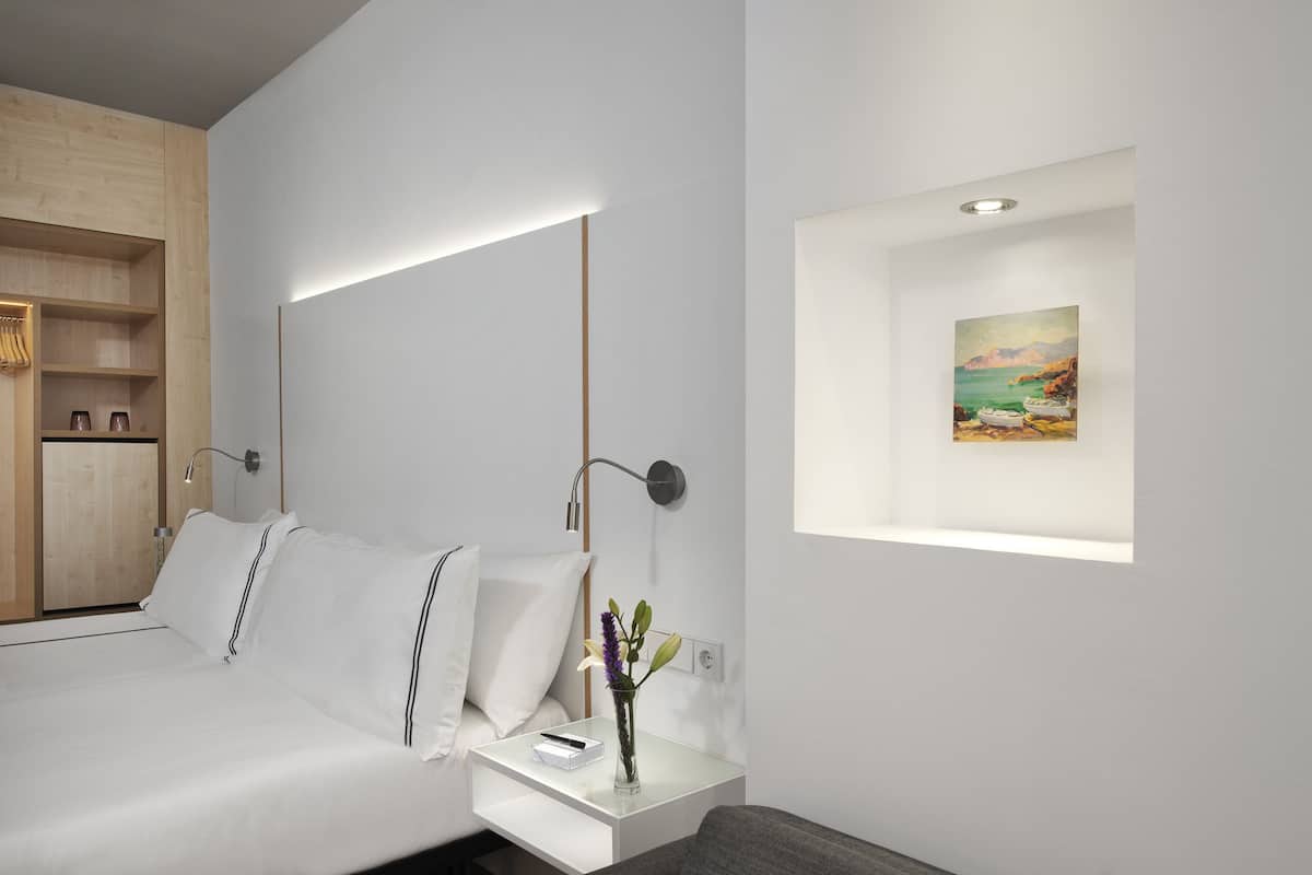 Ein modernes Schlafzimmer mit Bett, Nachttisch, Lampe und einem Bild an der Wand.