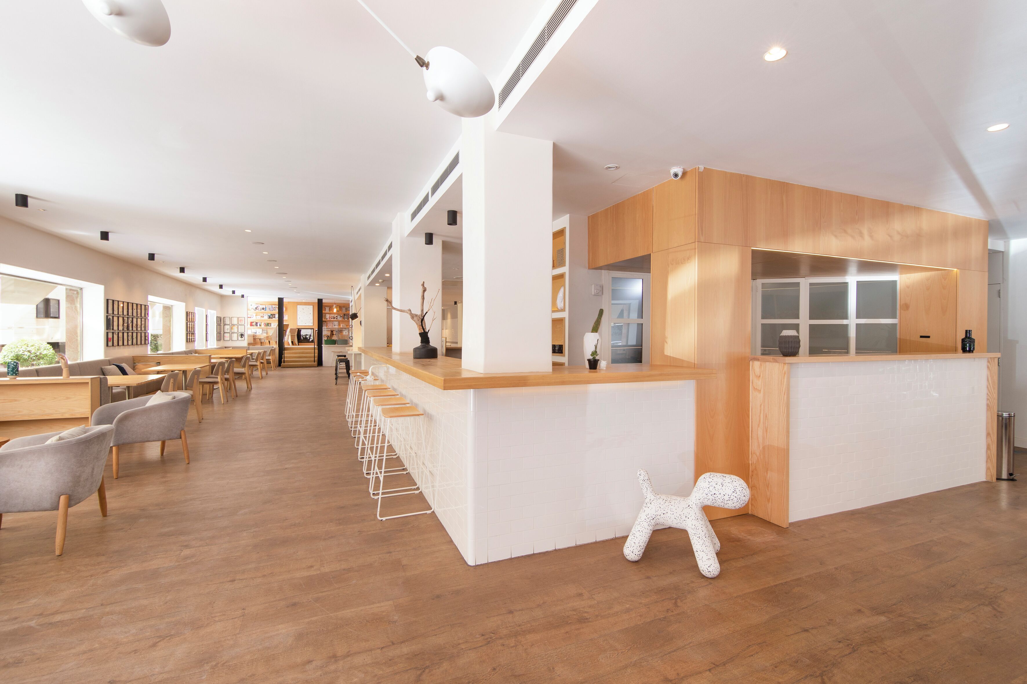 A modern interior with a reception desk, seating area, and a unique white sculpture.