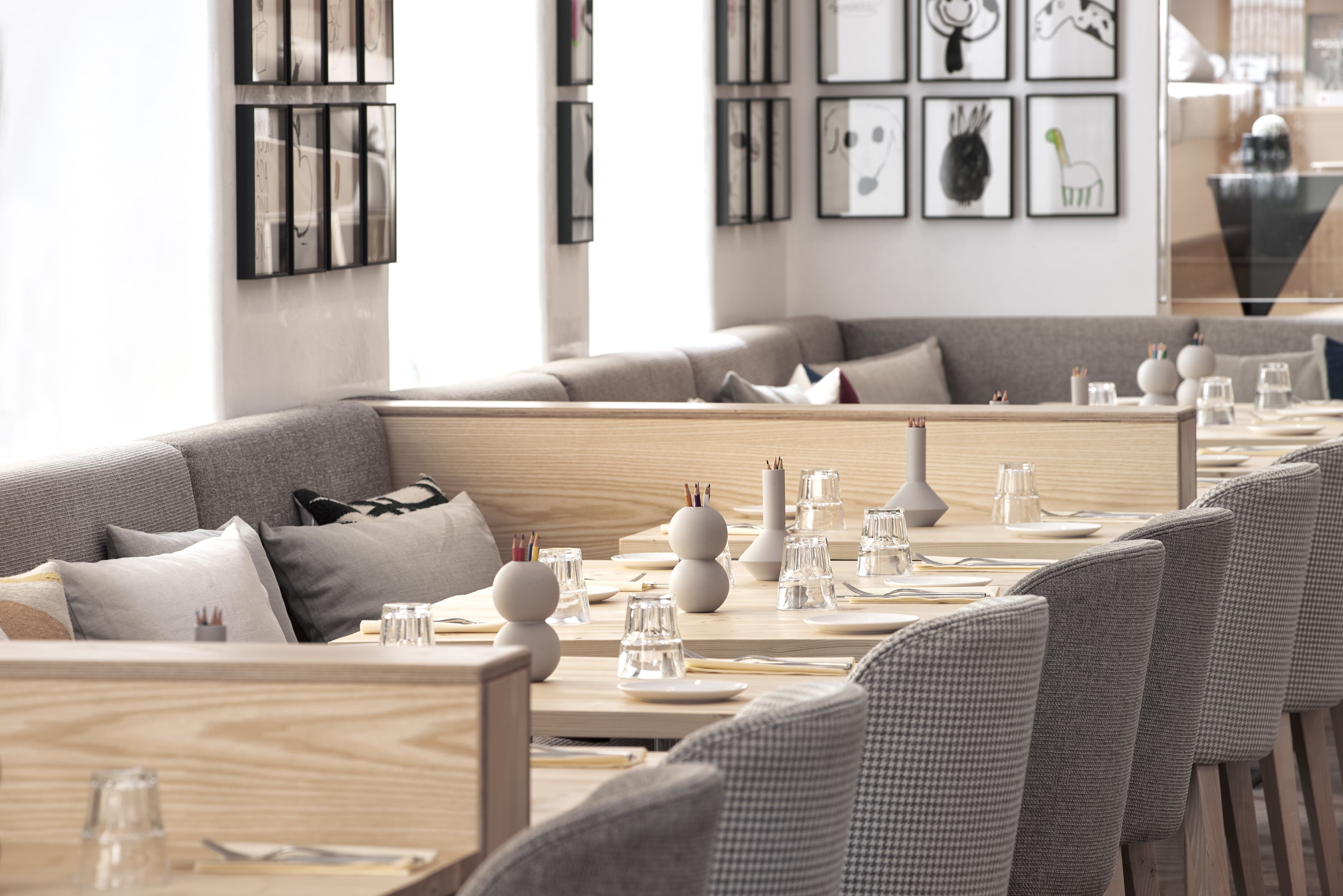 Un restaurante moderno con un amplio comedor, asientos tapizados en gris y una decoración minimalista.