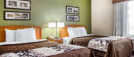A hotel room with two beds, a nightstand with a lamp, and framed pictures on the wall.