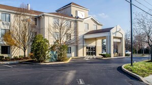 A modern building with a large entrance, a covered area, and a parking lot.