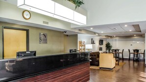 A hotel reception area with a black reception desk, a clock, and a sign that reads "SLEEP INN & SUITES".