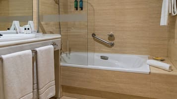 Een badkamer met een badkuip, een glazen douchecabine, een wastafel met spiegel en een handdoekrek.