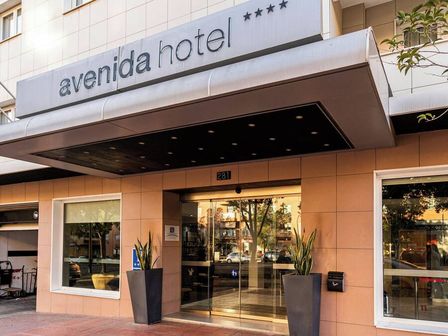 The exterior of the Avenida Hotel with a clear entrance, a signboard, and a number 281 on the facade.